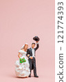 Miniature bride and groom figurine with the groom tipping his hat and the bride holding a bouquet of flowers 121774393