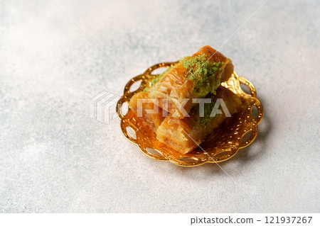 Delicious baklava served on an ornate gold tray showcasing its rich flavors and textures 121937267