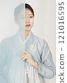 A beautiful woman wearing a luxurious and elegant Hanbok, standing behind a blue cloth 121016595