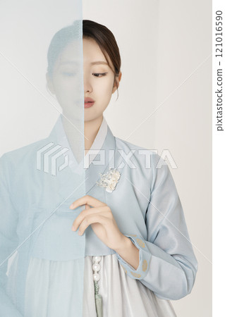 A beautiful woman wearing a luxurious and elegant Hanbok, standing behind a blue cloth 121016590