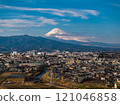 Majestic Mount Fuji overlooks a vibrant Japanese city, showcasing the perfect harmony of nature and urban development beneath a clear blue sky 121046858