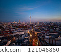 Berlin TV tower, a striking landmark, looms over the cityscape at dusk, illuminating the urban skyline with a warm glow from an aerial view 121046860