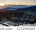 Breathtaking panoramic sunrise over Geneva city with Lake Geneva, moored boats, buildings, and snow capped Alps mountains in the background 121046884