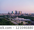 Aerial view of Fort Worth, Texas at dusk, vibrant cityscape, prominent skyscrapers, modern low residential buildings, active rail yard, and lush greenery 121046880