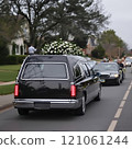 Funeral procession with black hearse and floral arrangement 121061244