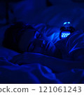 Young caucasian female sleeping peacefully at night with digital clock displaying 22:00 121061243