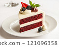 Slice of red velvet cake topped with fresh berries, whipped cream, and decorative accents 121096358