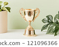 Shiny golden trophy surrounded by plants against a soft background 121096366