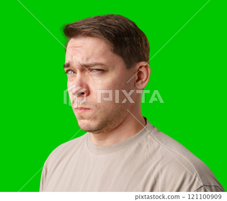 A man stands with arms crossed and a thoughtful expression in front of a green screen 121100909