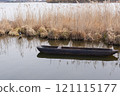 A traditional wooden dugout canoe floating on a calm lake, surrounded by tall reeds and natural scenery 121115177