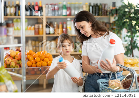 Checking expiration date of milk - mother and daughter checking qr code on bottle of milk 121140051