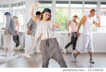 Group of energetic hip hop dancers focused on training while gathered together in spacious dance hall 121146592