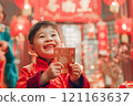 A smiling child eagerly holding up a Hong Bao envelope 121163637