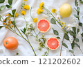 Colorful arrangement of citrus fruits and bright flowers on fabric 121202602