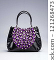 A black purse with purple crystals on it 121268473