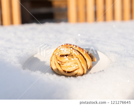 Fresh swedish cinnamon roll on a white plate in winter sun 121276645