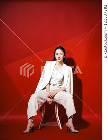 A career woman wearing a white pantsuit against a bright red background 121337892