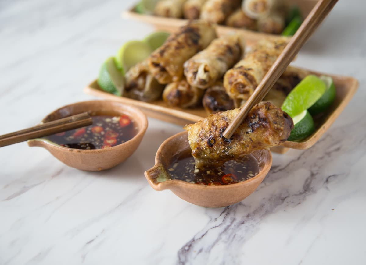 A Vietnamese fried spring roll being dipped into nuoc cham.