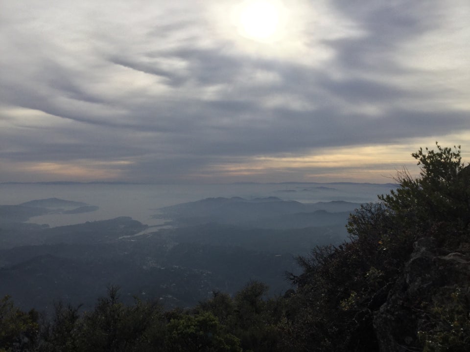 Very hazy and foggy view of the bay and a barely visible outline of downtown San Francisco, one tower of the Golden Gate Bridge, and Sutro Tower in the distance, from the top of Mount Tam’s East Peak.