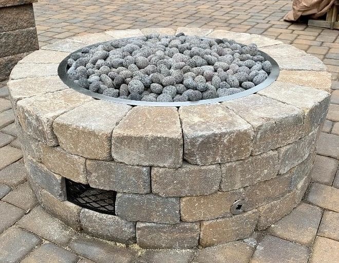 A fire pit with rocks in it sitting on top of brick.