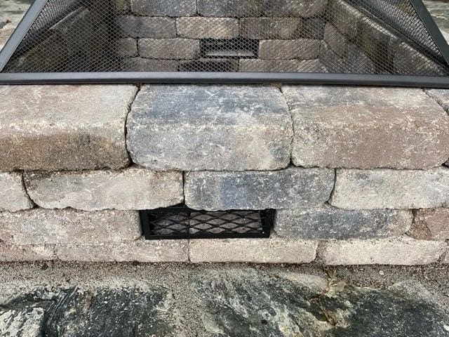 A stone wall with a metal grill on the side.