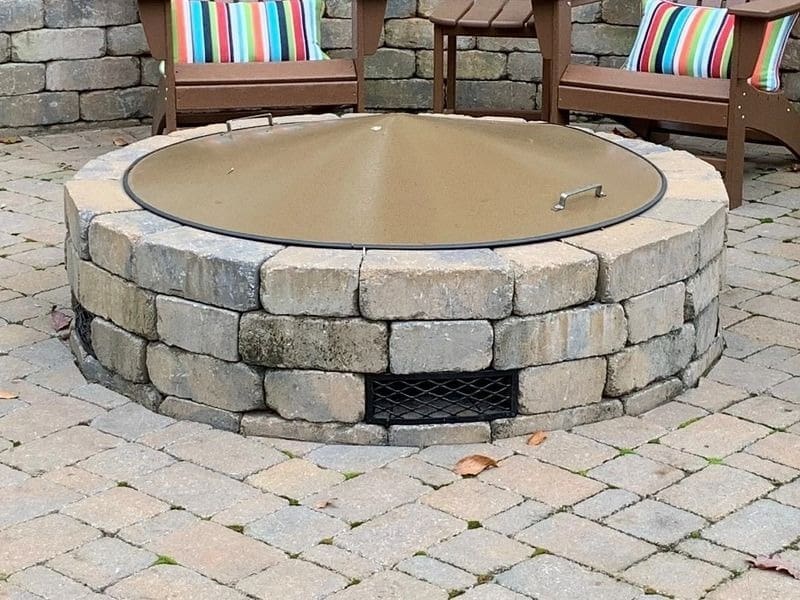 A fire pit with an open lid on top of it.