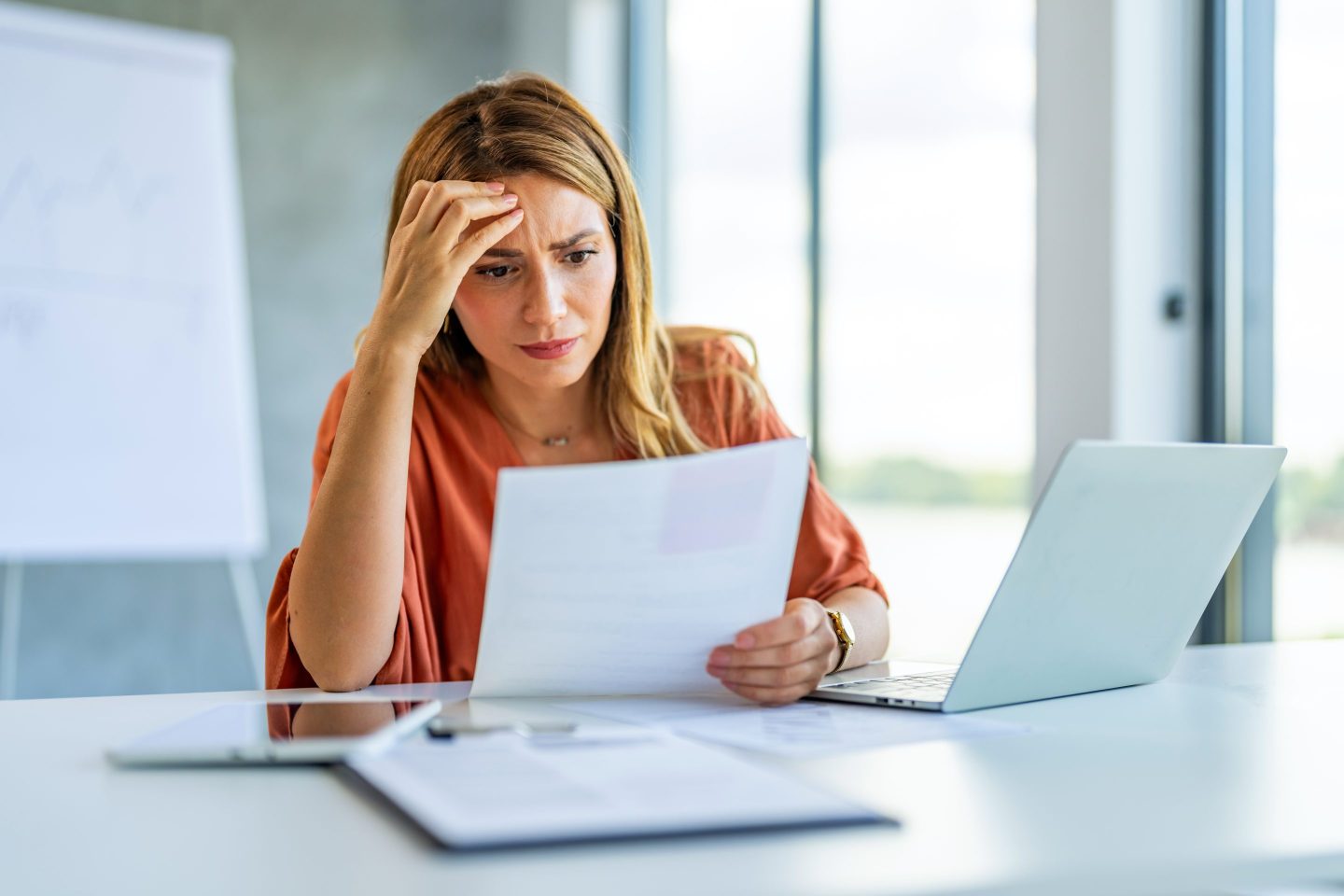 Frustrated and sad business woman holding financial report in hand.