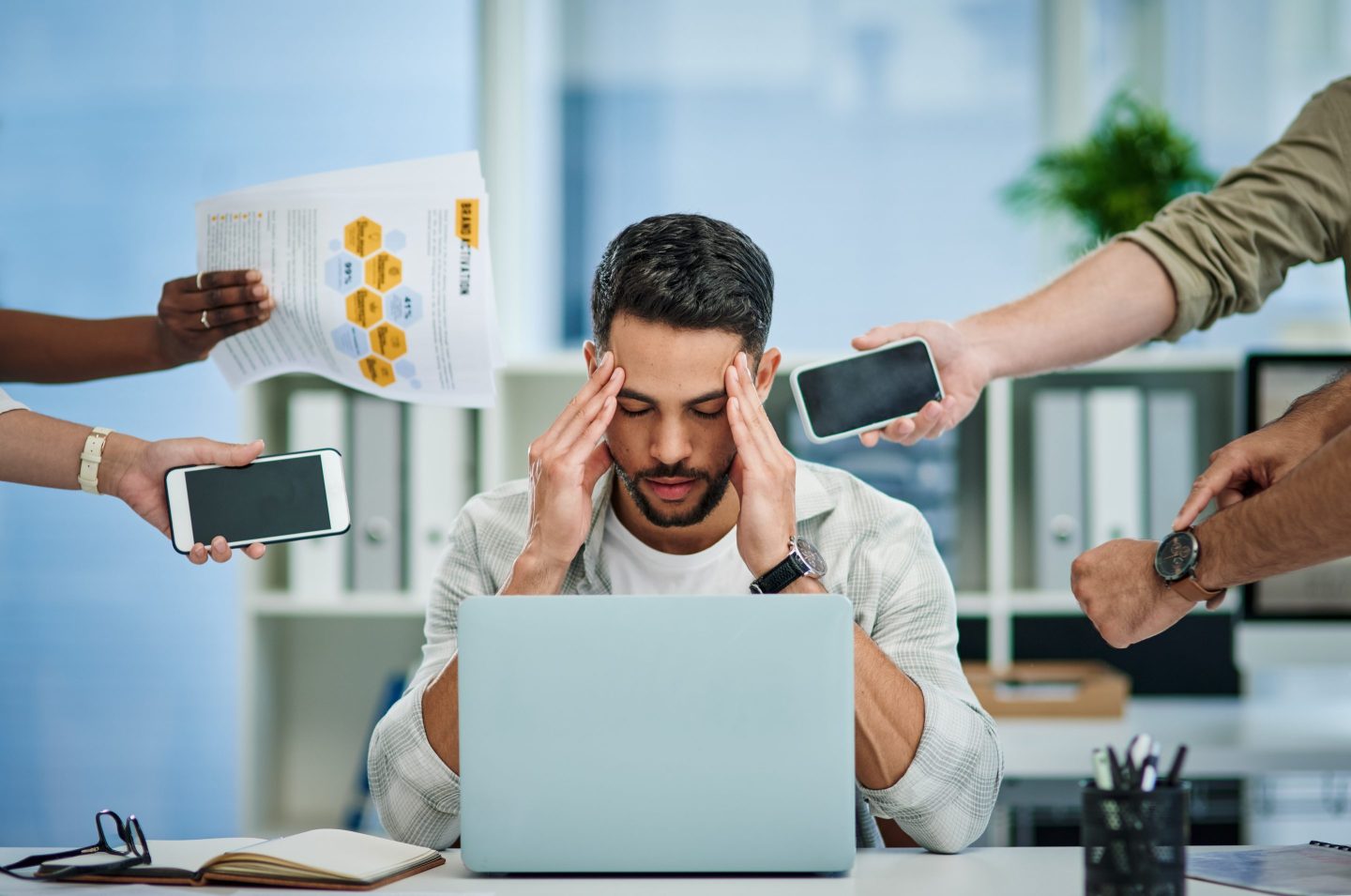 young man experiencing a headache at work while being overwhelmed