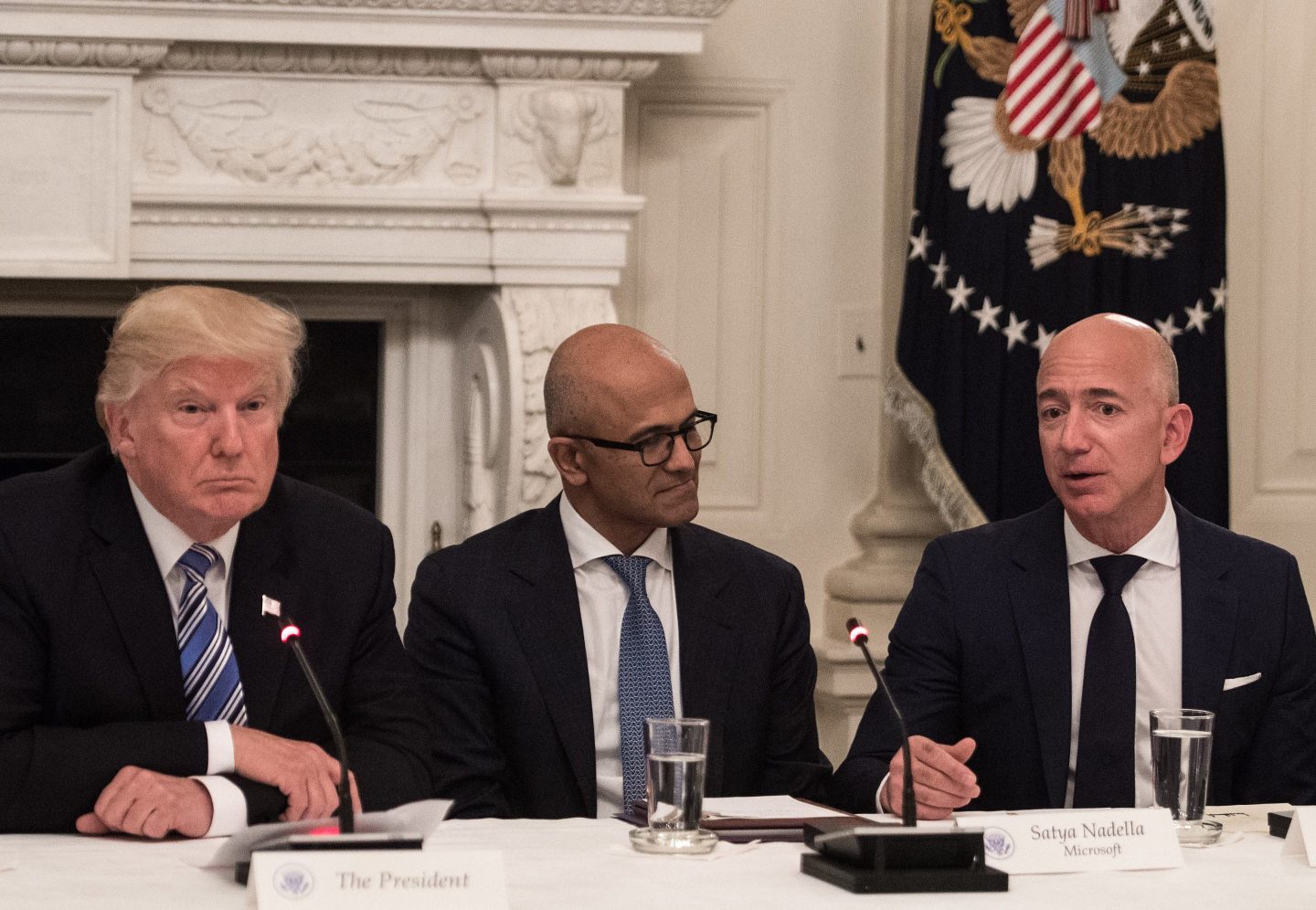 US President Donald Trump (L) and Microsoft CEO Satya Nadella (C) listen to Amazon CEO Jeff Bezos (R) during an American Technology Council roundtable at the White House in Washington, DC, on June 19, 2017. / AFP PHOTO / NICHOLAS KAMM        (Photo credit should read NICHOLAS KAMM/AFP via Getty Images)