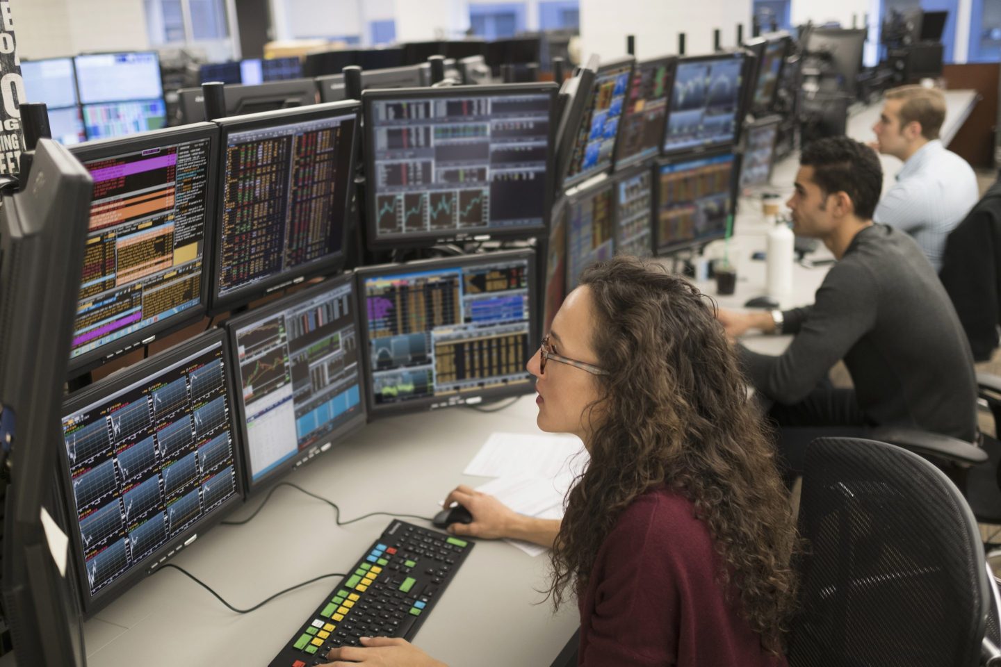 A woman stares at screens with financial data