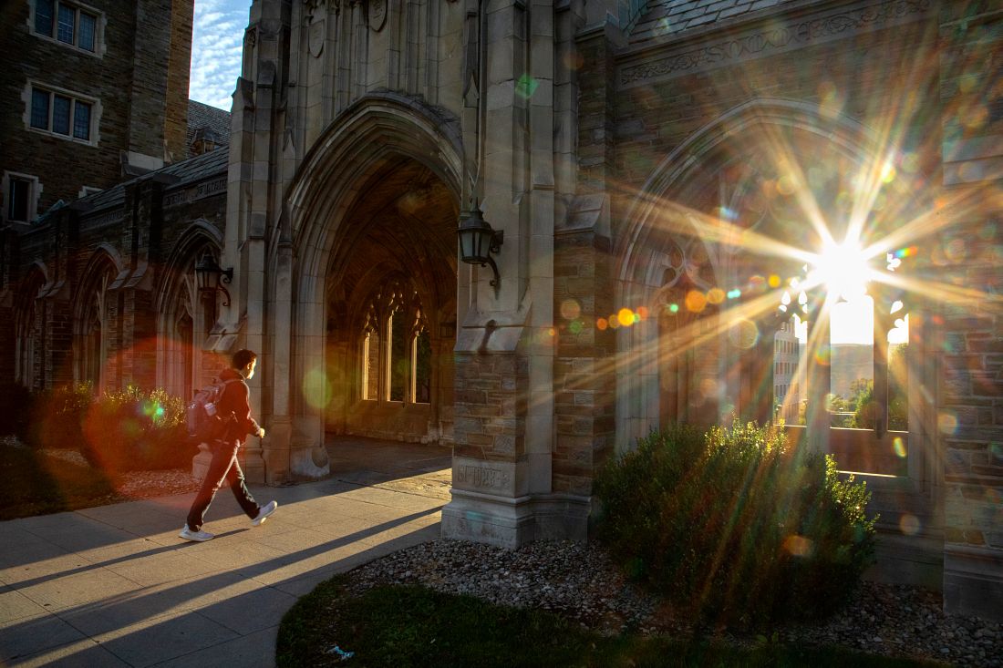 Student walking on campus at early evening.