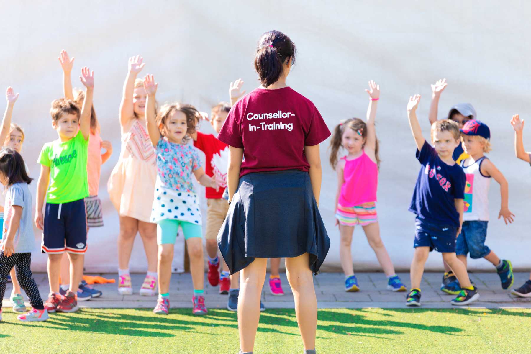 Camps counsellor with a group of children outside.