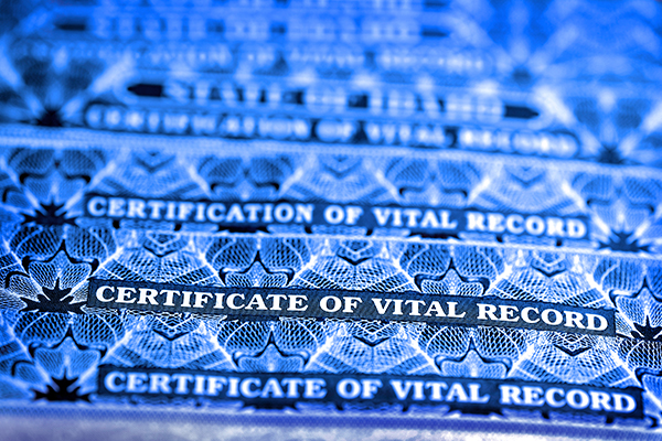 A close-up view of several official vital record certificates with a blue overlay.