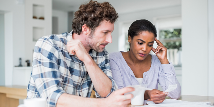 A photo of a young couple working on their bills at a table at home.