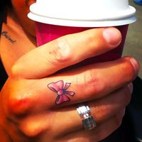 Bow on Middle Finger Tattoo Idea - A cute little bow tattoo on the girl's finger.