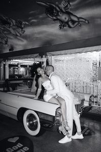 Black and white photo of a bride and groom with the Pink Cadillac at Little White Wedding Chapel. See more editorial elopement style ideas, editorial elopement poses, and editorial elopement photography. Book Kyra for your editorial Vegas elopement photos at riskyexposurephotography.com!