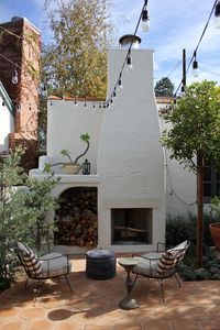 The exterior patio conjures an Italian piazza with bistro lights strung overhead, and a pair of modern steel frame chairs flank an outdoor fireplace.