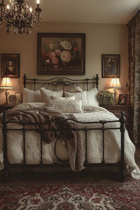 An Italian-style bedroom, with a large wrought-iron bed, luxurious linens, and rich, warm colors, soft lighting creating a cozy atmosphere. Background includes an antique dresser, ornate wall art, and a plush rug. Light coming from a chandelier with intricate detailing, casting gentle shadows. Created Using: classic Italian design, warm color palette, rich textures, high detail, hd quality, elegant aesthetics, inviting environment