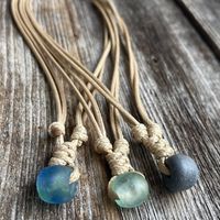 This list features a natural necklace made of waxed cord and a green sea glass. It has an adjustable closure.