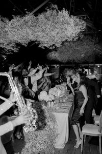 Discover love at Quinta da Bella Vista through Alice Vicente's lens. Timeless weddings in Portugal. Romance, nature, and unforgettable moments. Guests dance to the sound of a saxophone being played during the reception inside the Greenhouse of Quinta da Bellavista destination wedding