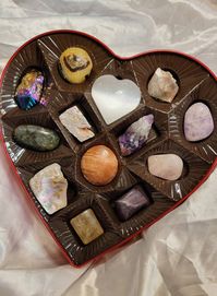 This beautiful box of rocks is a delightful alternative to a traditional box of chocolates. This box comes with a polished selenite heart, natural lithium quartz, polished labradorite, natural raw super seven crystal, rose quartz, pink moss agate, ruby in kyanite, titanium coated crystal, orange selenite, optical calcite, septarian nodule, Amethyst, and rainbow abalone shell, as well as a mystery surprise piece of handmade jewelry (made with gemstones and sterling silver) Each crystal and minera