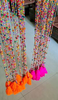 Multi coloured beaded pink and orange mixed large tassels curtains strings.  Beautiful and colourful fuchsia pink and bright orange tassels curtains.  These strings are made of various glass beads, wood, plastic and acrylic beads and acrylic thread tassels.  These colourful, vibrant strings are perfect to elevate your mood for the day. These strands genuinely look beautiful and perfect for the Bohemian décor for the Summers. Ideal on the doors and windows. The curtain comes with 10 long strings,