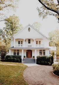 Dream house. Modern farmhouse. White House with wraparound porch, wood door, upper balcony, large windows.