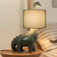 Brighten up your little ones space with this dinosaur shaped table lamp. The ceramic base comes with a matching braided flex and fabric drum shade. Give your child's bedroom a pop of colour in a subtle and fun way. The in-line rocker switch provides convenient control, making it easy to illuminate your space. Help your child overcome the fear of darkness and create a comfortable sleep environment with this playful lamp. Finish: Green