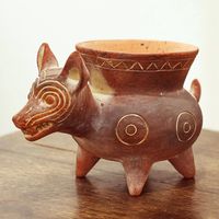 This dog-themed pot is inspired by an archeological piece depicting a Colima dog a Mesoamerican domesticated animal that was shorter and thicker than the Aztec xoloescuincle dogs that still exist today. These short pot-bellied effigies have been found in shaft tombs throughout the southern state of Colima hence their name. The original piece can be found at Mexico's national Anthropology Museum. This ceramic version is crafted by the Angel Ceron Artisan Association.