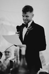 Groom in black tie reading out his wedding speech | outdoor wedding | groom speech | boho styling | black tie event | marquee wedding | Carrie Lavers Photography