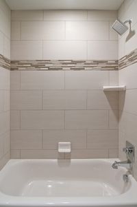 We love oversized subway tiles in this bathroom! The addition of glass accent tiles gives the space a custom look without being over the top. This is perfect for your secondary bathrooms. We also love the square showerhead from the #deltafaucet Dryden collection.