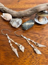 The 'Mermaid's Delight' earrings will transport you to a warm day at the coast with your toes in the sand and the sunlight glinting off the waves. Two different small shells dangle at the bottom of each earring. Mother of pearl, freshwater pearl, heishi shell, and peach and cream colored round shell beads, and white, matte cream, and reflective gold glass seed beads decorate them. They are light weight, unique, and made with beautiful natural treasures. You may not be able to be at the beach everyday, but you can wear a little bit of it through your everyday life!