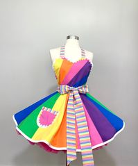 You are a walking (possibly dancing) bright, colorful rainbow in our Color Me A Rainbow Apron!! The bodice is a rainbow design featuring the colors of the rainbow striped waistband and ties- yellow, orange, pink, purple, blue and green. The 16- gore circle skirt doubles down on the rainbow effect and is fully lined. The whole design is very feminine, flirty, and fun! So many twirl days ahead!! The bodice is fully lined. The ranbow striped neck straps are adjustable with a D-ring. Waist ties are