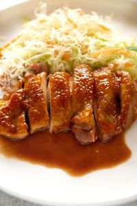 Hero shot of Teriyaki chicken on a white plate with shredded vegetables.